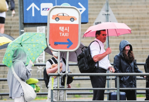 近日,在韓國首爾站外,人們在雨中排隊等出租車。受臺風